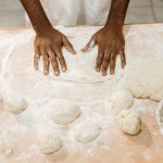 Plan recadré du boulanger afro-américain pétrissant la pâte pour la pâtisserie sur la table salissante