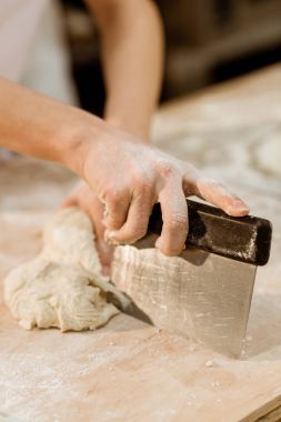 cropped shot of baker cutting dough with dough knife clipart