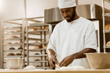yakışıklı Afro-Amerikan baker üretim pişirme üzerinde hamur hazırlama