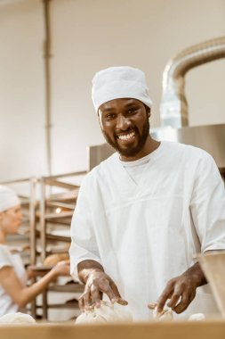 yakışıklı Afro-Amerikan baker üretim pişirme üzerinde hamur yoğurma