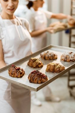 Genç baker tepsi imalatı ekmek, taze kruvasanlar ile tutarak yakın çekim çekim