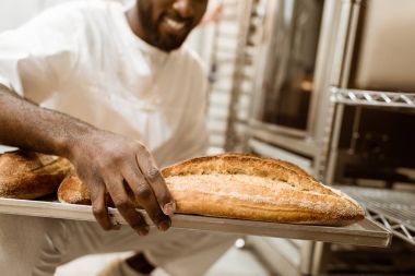 Afro-Amerikan baker bir bardak taze somun ekmek üretimi pişirme üzerinde tepsisi ile kırpılmış