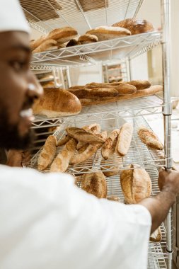 Afro-Amerikan baker rafları taze ekmek üretimi pişirme üzerinde sürüş, yakın çekim vurdu