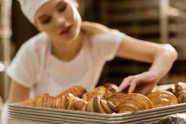 genç kadın baker üretim pişirme üzerinde taze pişmiş kruvasanlar incelenmesi yapıyor yakın çekim çekim