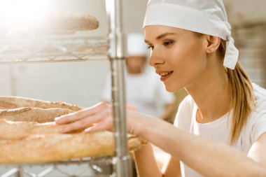 genç kadın baker üretim pişirme üzerinde taze pişmiş ekmek somunları incelenmesi yapıyor