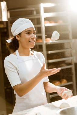 genç kadın baker üretim pişirme yemek yaparken çiğ hamur atma