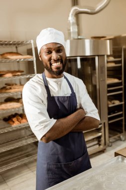 Afro-Amerikan baker üretim pişirme üzerinde çapraz kollar ile gülümseyen