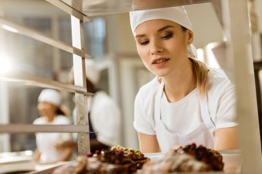 güzel Bayan baker taze pişmiş kruvasanlar tepsi üretim pişirme üzerinde seyir