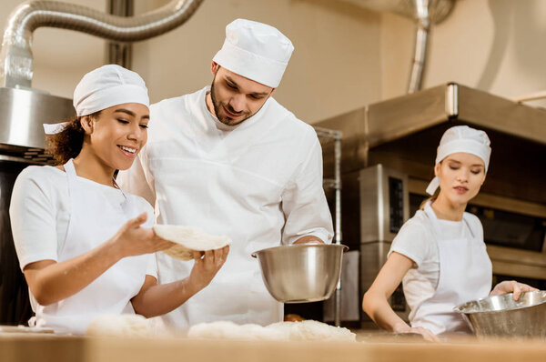 young multiethnic team of bakers working together at baking manufacture