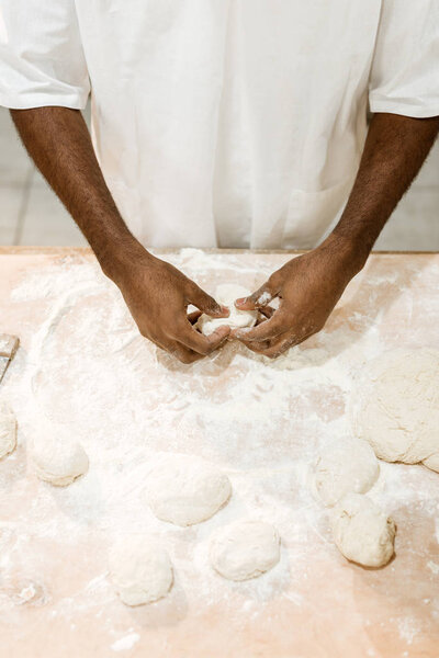 cropped shot of african american baker preparing dough for pastry