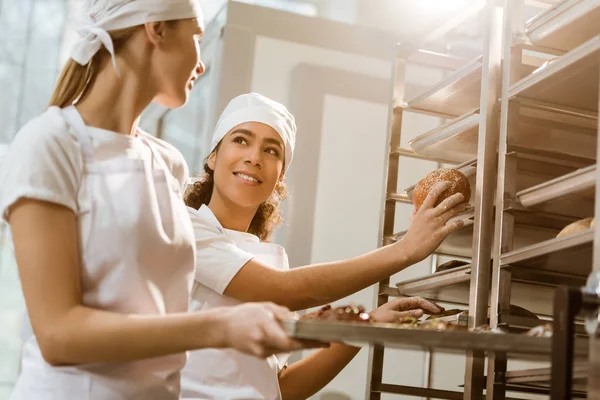Panaderos Femeninos Felices Poniendo Pastelería Fresca Los Estantes Fabricación Hornear — Foto de Stock