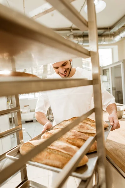 Happy Young Baker Putting Trays Fresh Bread Stand Baking Manufacture — Free Stock Photo