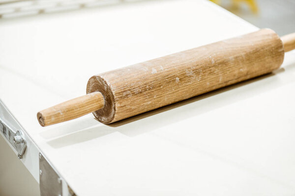 Close-up shot of wooden rolling pin on white table