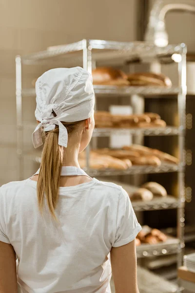 烘烤生产中的年轻女面包师的后视 — 图库照片