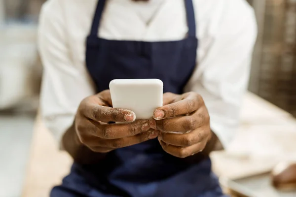 Potongan Kue Afrika Amerika Dengan Tangan Terbungkus Tepung Menggunakan Smartphone — Stok Foto