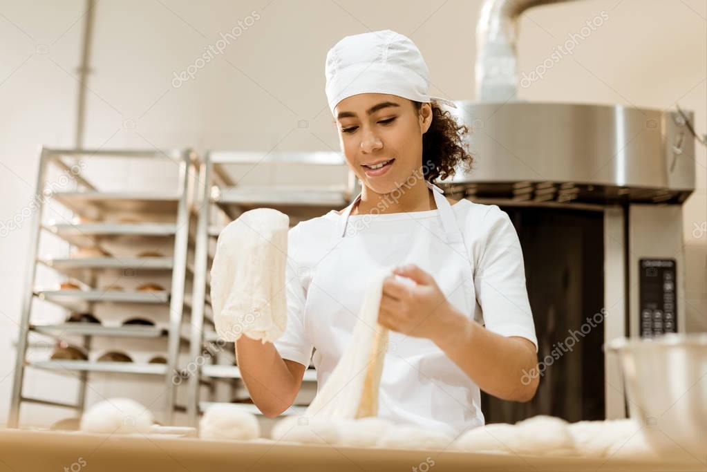 female baker preparing dough for pastry on baking manufacture