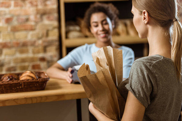 young woman with paper bags at pastry store