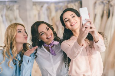 Gelin ve düğün atelier akıllı telefon selfie alarak nedime gülümseyen genç