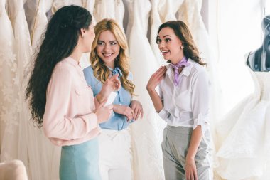 Female friends chatting about dresses in wedding fashion shop