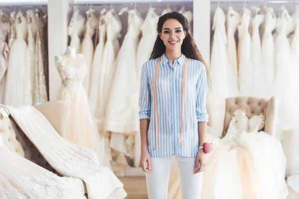 Young female tailor standing in wedding atelier