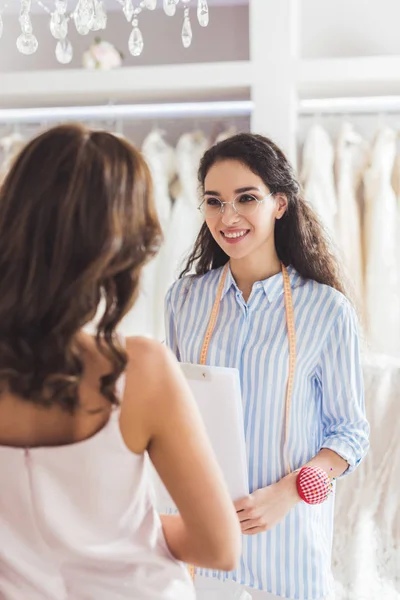 Bride in lace dress and tailor in wedding salon