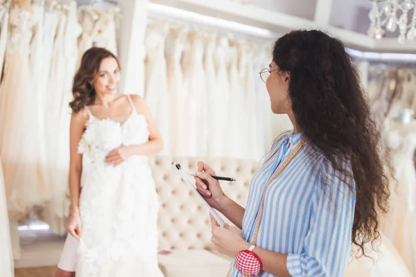 Needlewoman 和新娘讨论婚纱时装店的服装设计 — 图库照片