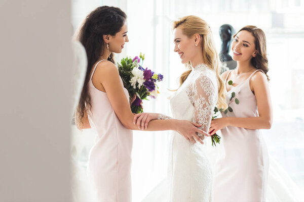 Happy women in wedding dresses with flowers in wedding salon