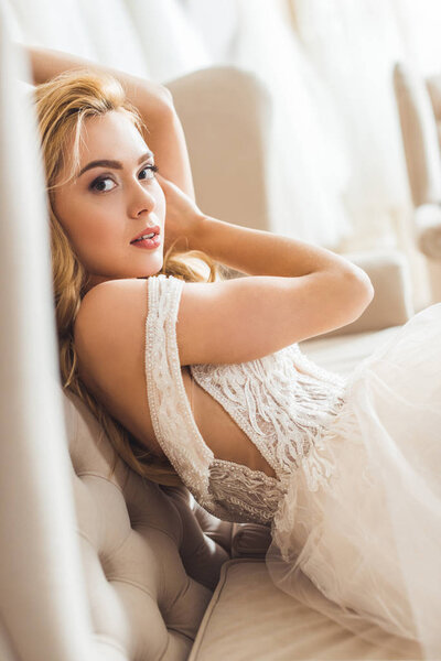 Привлекательная невеста отдыхает на диване в свадебном ателье
