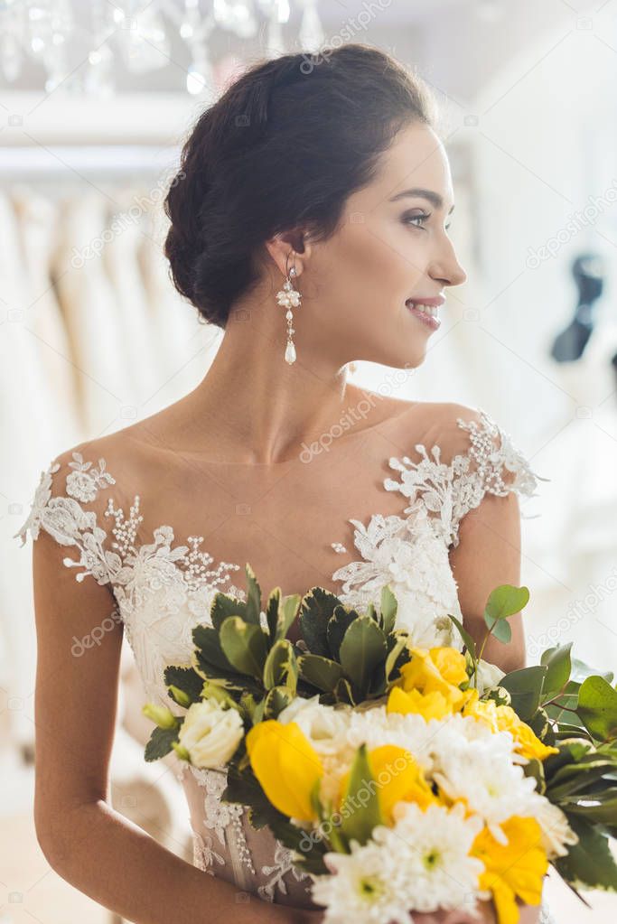 Beautiful bride with floral bouquet in wedding atelier