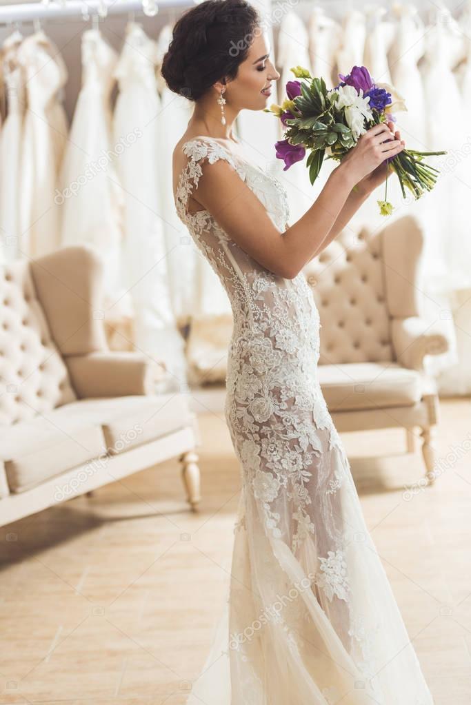 Beautiful bride with floral bouquet in wedding salon