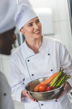 kase sebze ile tutarak ve uzak lokanta mutfağı seyir gülümseyen Şef