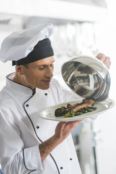 在餐馆厨房嗅到食物的英俊的厨师 — 图库照片