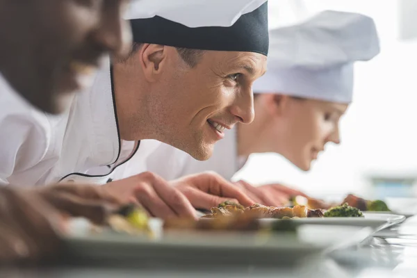 Sorrindo Chefs Multiétnicos Farejando Comida Cozida Cozinha Restaurante — Fotografia de Stock