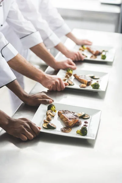 Imagen Recortada Chefs Multiétnicos Con Platos Con Filetes Cocina Del — Foto de stock gratuita