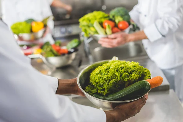 Bijgesneden Afbeelding Van Multiculturele Koks Houden Kommen Met Groenten Bij — Stockfoto