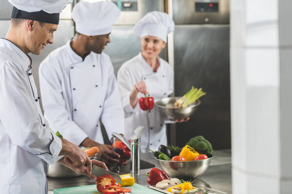 smiling multicultural chefs preparing food at restaurant kitchen