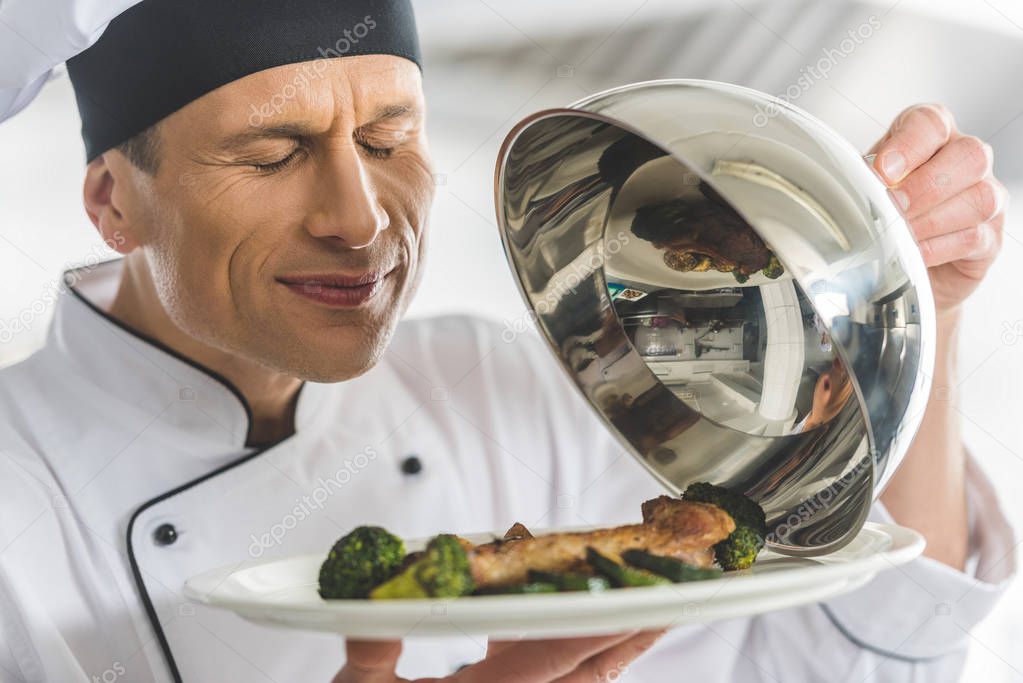 handsome chef sniffing dish at restaurant kitchen with closed eyes