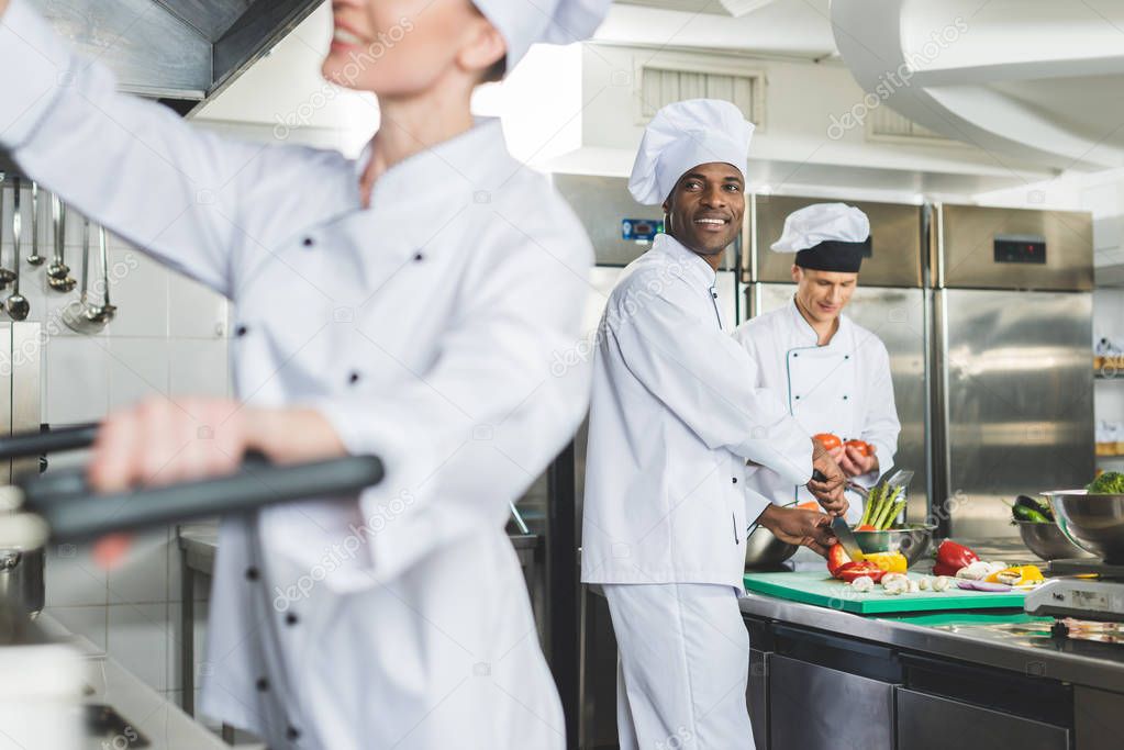 smiling multicultural chefs cooking at restaurant kitchen