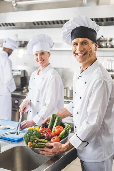 Uśmiechający Się Kucharzy Patrząc Kamery Restauracji Kitchen — Zdjęcie stockowe