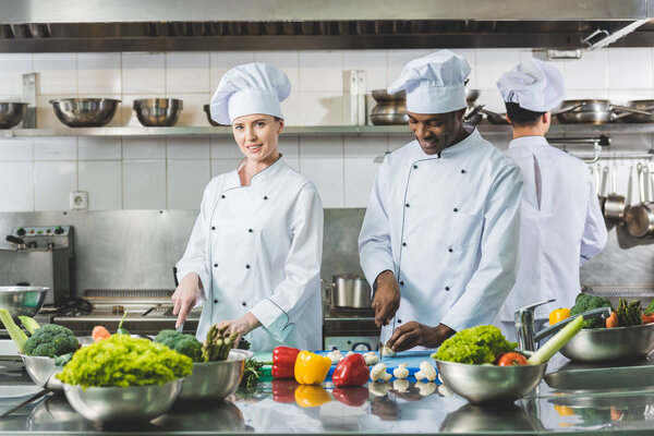 multicultural chefs cutting vegetables at restaurant kitchen