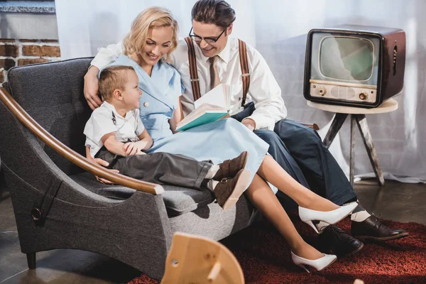 mutlu 1950'ler tarzı aile kanepede oturan ve birlikte kitap okuma
