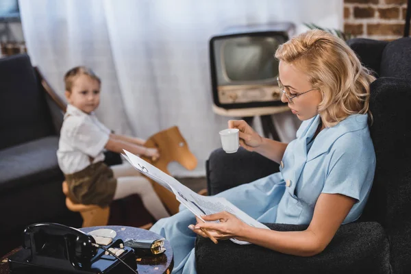 Woman Eyeglasses Holding Cup Coffee Reading Newspaper While Little Son — Stock Photo, Image