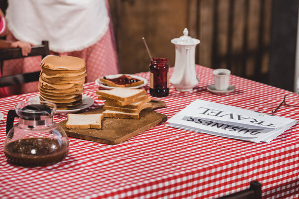 close-up view of tasty breakfast with toasts, pancakes, newspaper and coffee on table