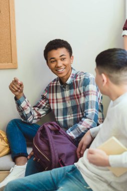Sınıf için okul tatilinde konuşmaya gülümseyen Afro-Amerikan lise öğrencisi