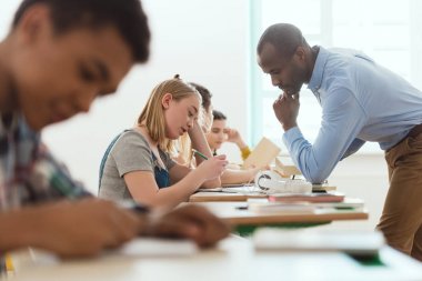 Çok kültürlü yazma okul ve Afrika kökenli Amerikalı öğretmen kontrol yan görünüm 