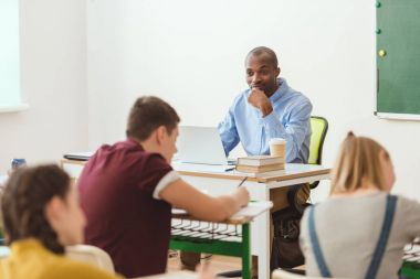 Okul ve öğretmen ile laptop ve kahve fincan masada oturan yazma 