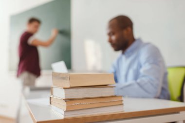 Yakın çekim kitap yığını öğretmen ve lise öğrencisi ile açık arka plan