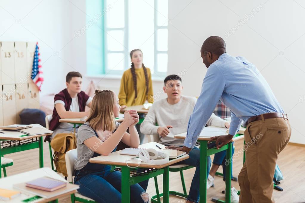 Rear view of african american teacher and high school teenage students in classroom
