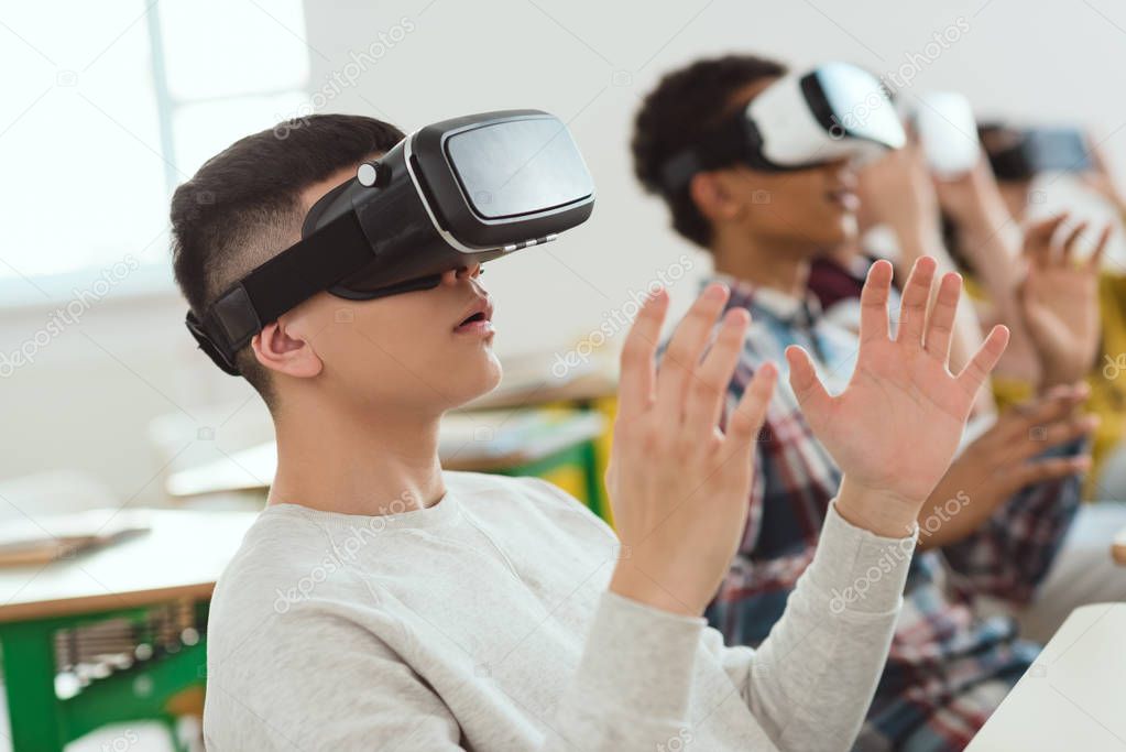 Side view of multicultural high school teenage students using virtual reality headsets 