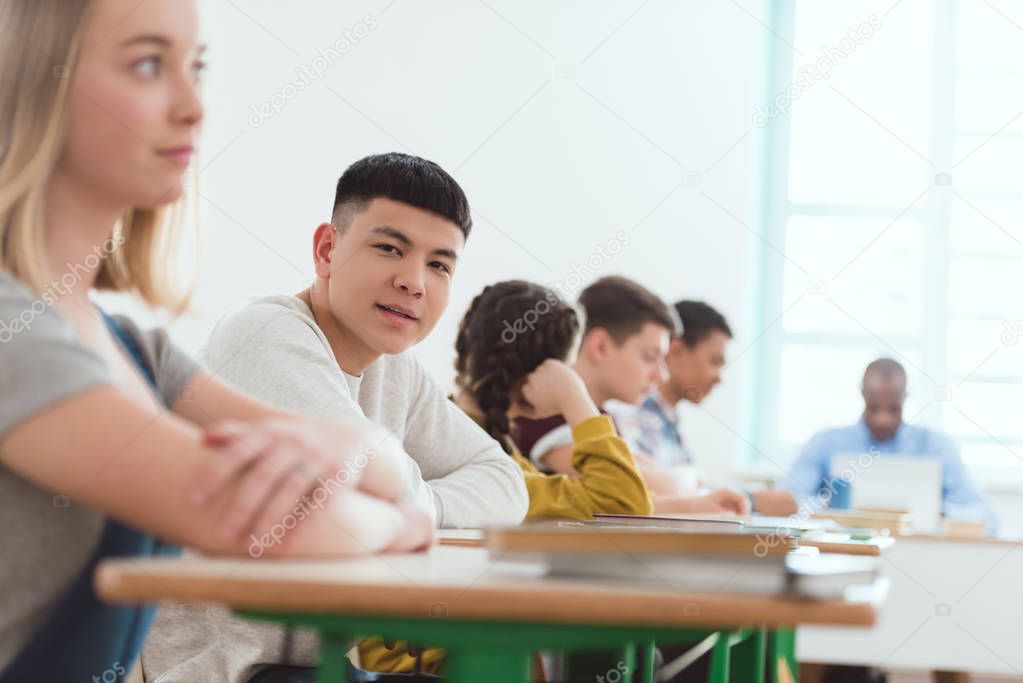 Portrait of high school teenage asian student with classmates and teacher sitting in classroom